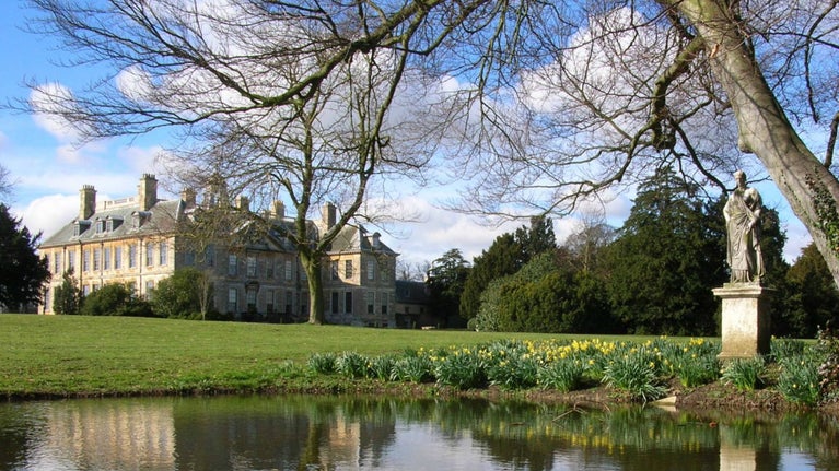 View of Belton House over the Mirror Pond in the Pleasure Gardens with daffodils